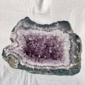 large slice of amethyst with bands of crystals and bedrock back