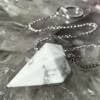 howlite pendulum with six sides, grey veining through the white opaque mineral on a white metal chain and ring