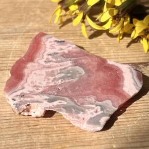 natural rhodochrosite slice, polished on two sides with rough edges and wavy patterns of pinks, greys and cream